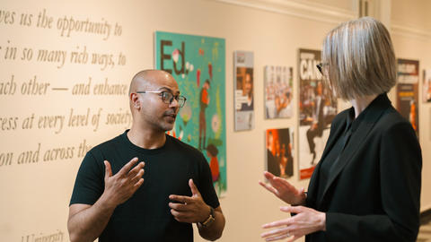 Two teaching colleagues chat in a hallway.
