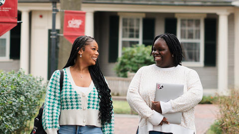 Two students chat and walk outside on the HGSE campus.